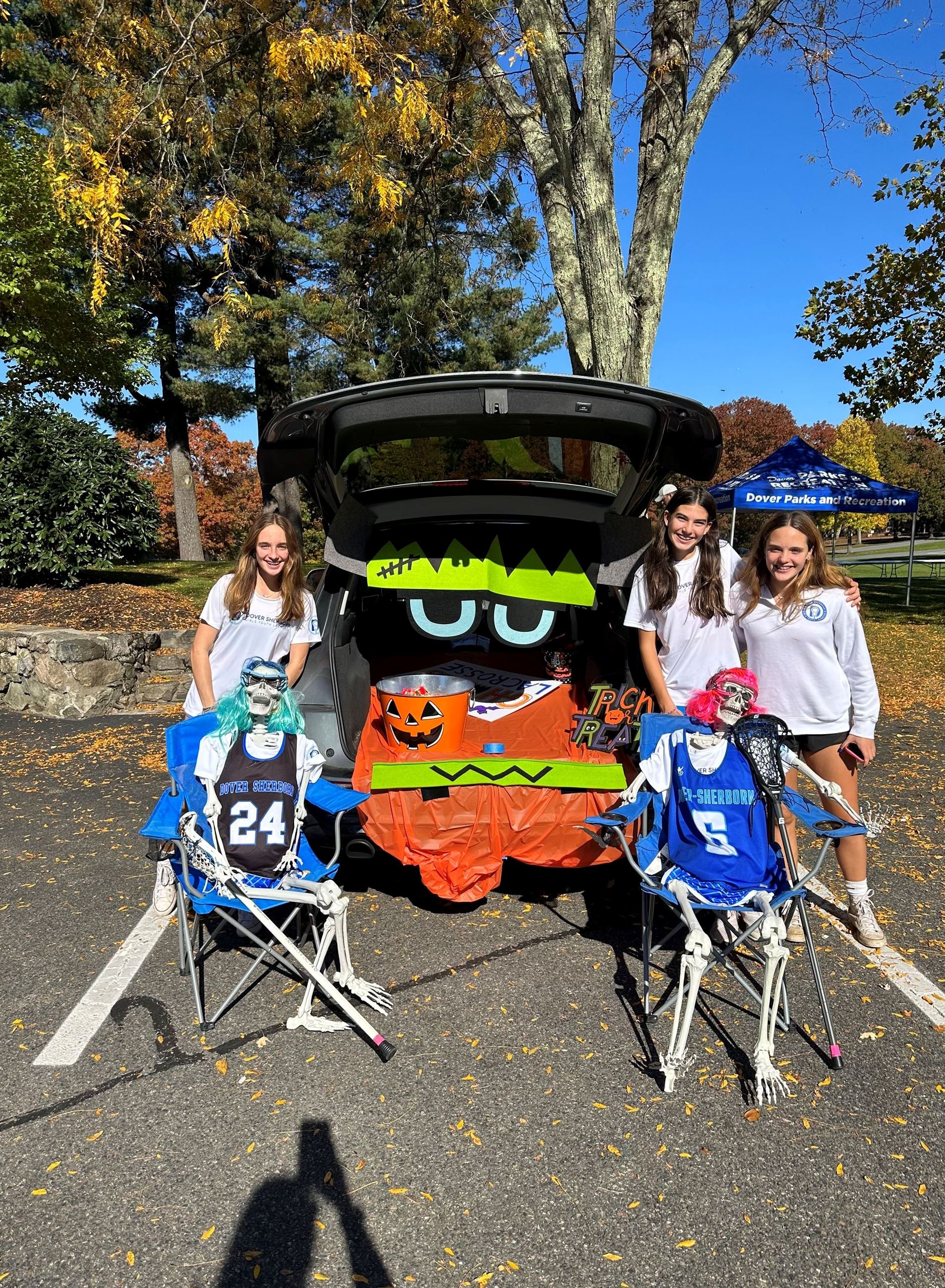 Photo with three girls posing with their trunk or treat decorated with skeletons 